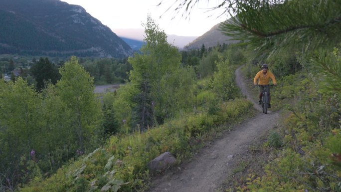 黎明时分，一位老人骑着电动自行车沿着山道行驶