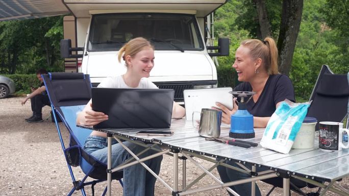 母亲和女儿在露营途中一边完成自由职业工作一边讨论股市