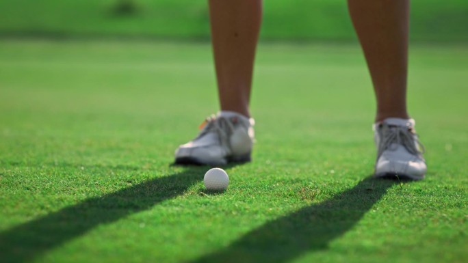 健康的女运动员在绿地球场打高尔夫球。高尔夫球手在室外击球