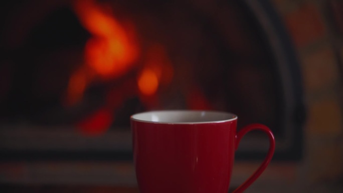 一杯茶的背景是燃烧着火焰的壁炉