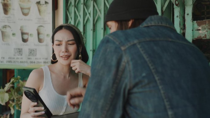 年轻夫妇在迷人的曼谷老城沉迷于街头甜点，用智能手机捕捉回忆。
