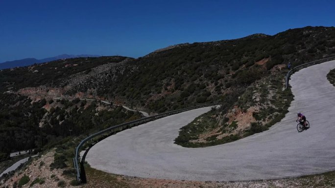 无人机4k剪辑与公路骑车人在风景秀丽的蜿蜒道路上，希腊凯法利尼亚岛