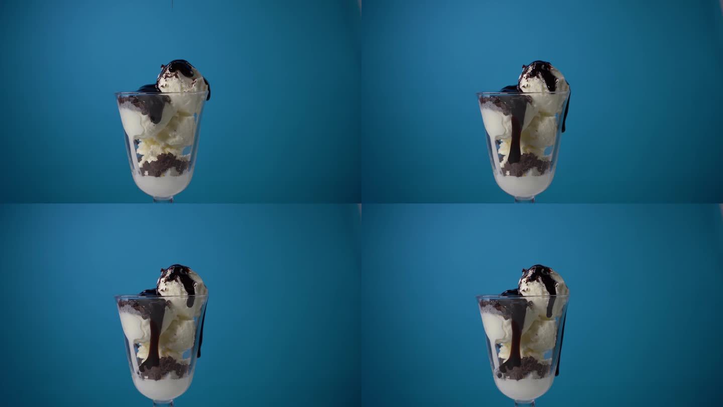 将巧克力糖浆倒入鲜奶油中，淋上蓝色背景的冰淇淋。冰淇淋广告。餐厅里美味的冰淇淋
