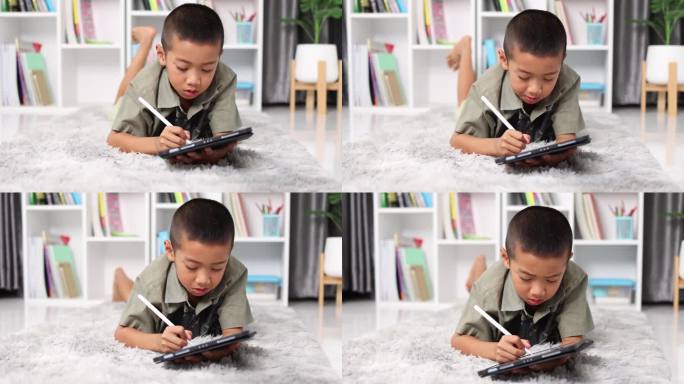 小男孩喜欢在电脑平板屏幕上用触控笔学习写字或美术绘画，带着做作业或回到学校的人在家里的pad上学习。