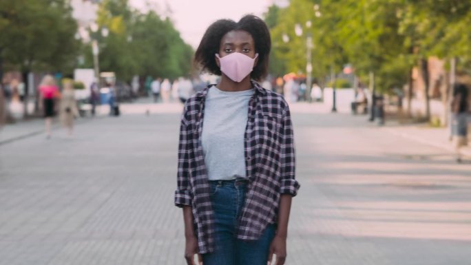 带着医用口罩站在城市街道上的迷人的非裔美国女士的缩倍延时肖像