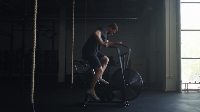 高强度的有氧运动，健硕男子在健身房的健身脚踏车上练习，健身俱乐部的训练