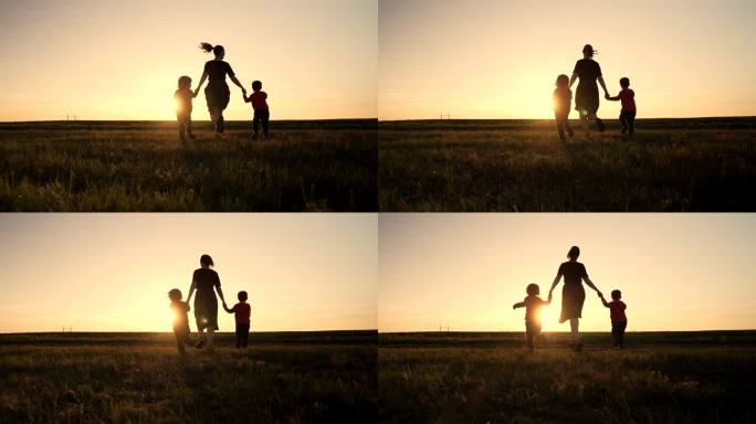 年轻家庭的剪影——妈妈和两个兄弟双胞胎男孩在露天运动场或公园跑向太阳，黄金时刻，闪耀着快乐的母亲和孩