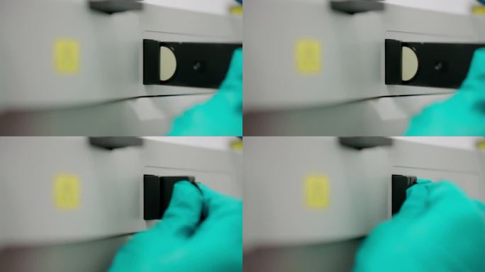研究人员戴着防护手套的手操作光学显微镜，同时将偏光片插入设备