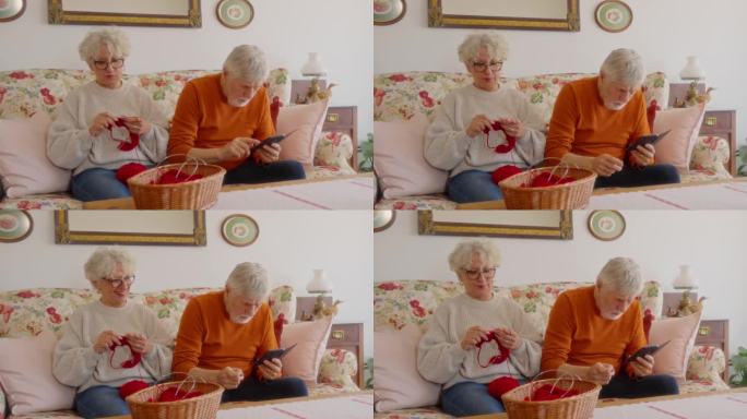 老年妇女在家客厅用手机在伴侣身边织毛衣