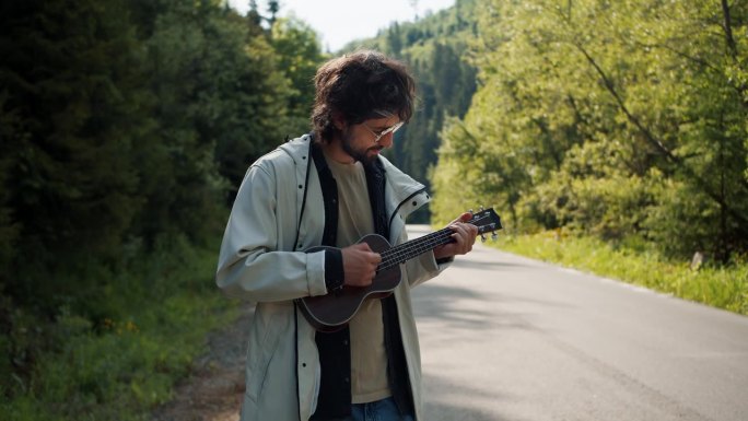 一位身穿白色夹克的黑发男子在山间徒步旅行时，在路边弹奏着弦乐器