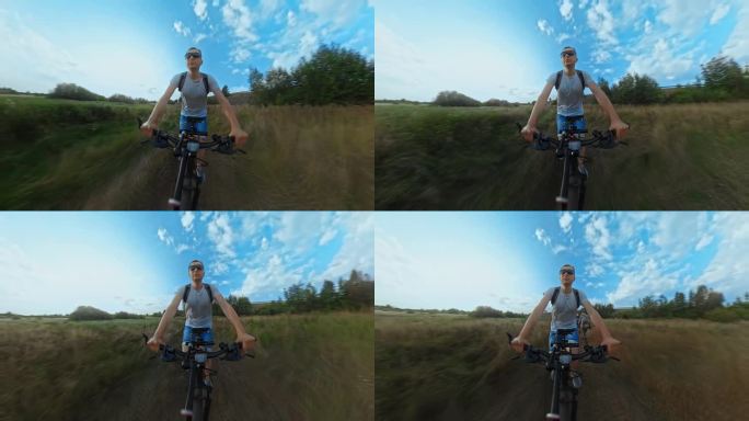 戴墨镜的男子沿着田野的小路骑越野山地车。用广角镜头拍摄的动作相机。第三人称前视。乘坐MTB自行车旅行