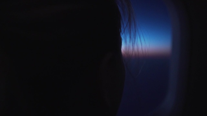 手持拍摄的十几岁的女孩从飞机上看在日出期间飞行颗粒