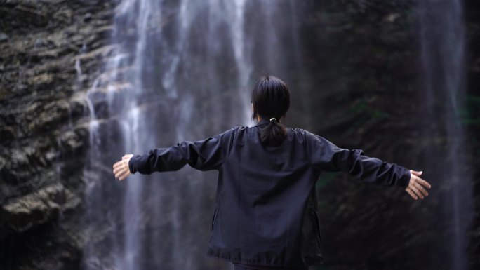 女性人物背影感受亲近自然登顶山峰瀑布水流