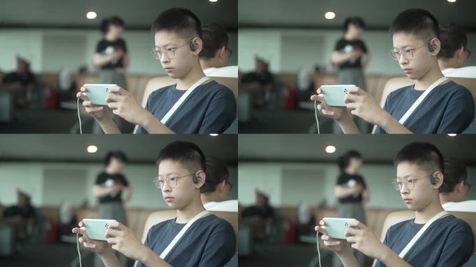 男孩暑假出游在机场候机大厅玩手机游戏