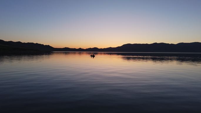 新疆赛里木湖清晨朝霞中划船捕鱼的人渔船