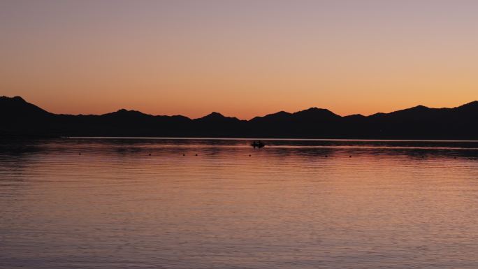 新疆赛里木湖清晨朝霞中划船捕鱼的人