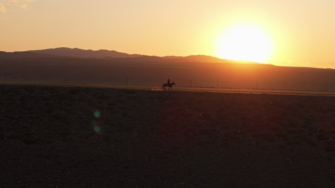 新疆伊犁昭苏草原上在夕阳下奔跑的马跟人