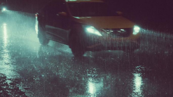夜晚暴雨中车灯照亮下落的雨水
