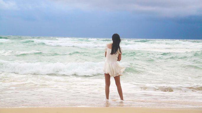 穿裙子的美女站在沙滩上