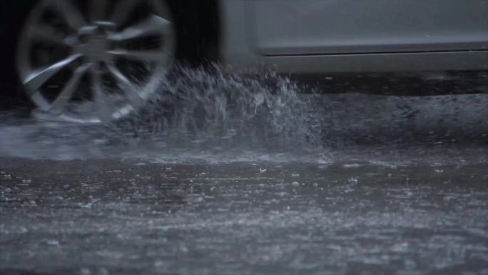 暴雨中急速通过积水溅起水花的车辆