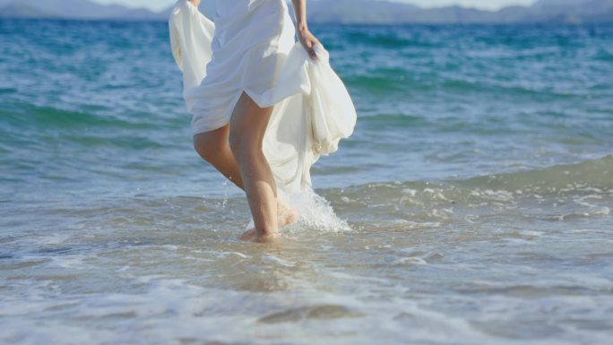 夏日海边，穿着白裙的女性在玩水