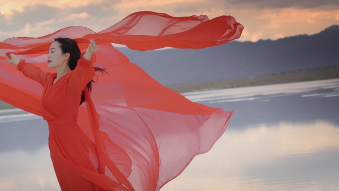 红色长裙飘扬的女人站在湖中红裙