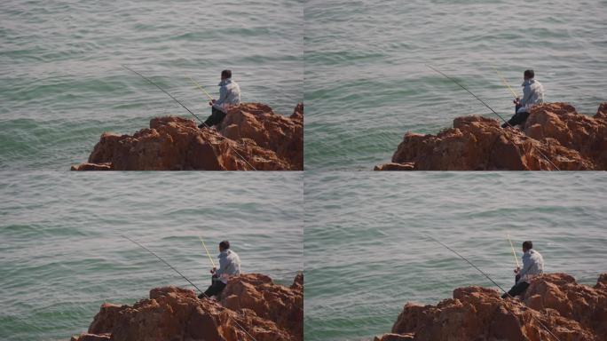 在海边岩石上钓鱼的人