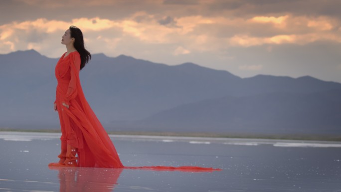 红色长裙飘扬的女人站在湖中红裙