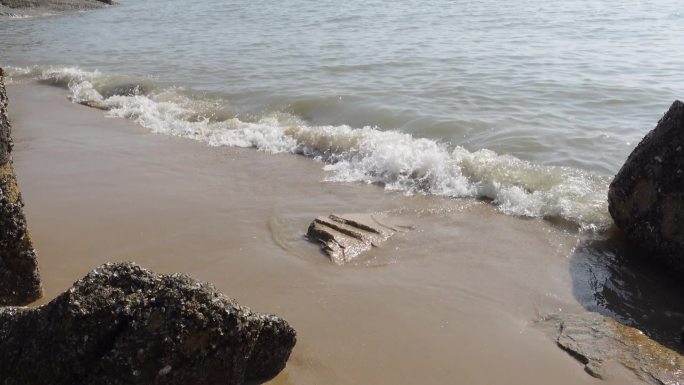 海边海浪沙滩浪花拍在沙滩上
