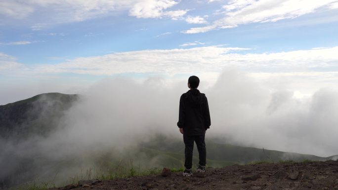 女性青年站在山顶看风景背影看远山感受自然