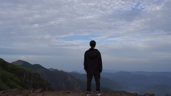 女性青年站在山顶看风景背影看远山感受自然