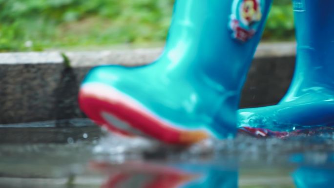 穿着蓝色雨靴的孩子在水坑中玩水