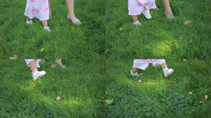 妈妈牵着孩子在草地学习走路