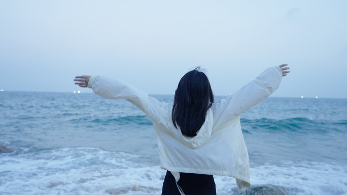 女孩展开双手拥抱大海感受自由和风