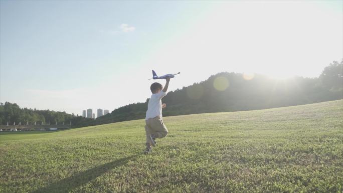 小男孩拿着飞机玩具草地奔跑欢乐童年儿童节