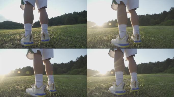 脚步特写踢足球站在草地上逆光剪影阳光少年