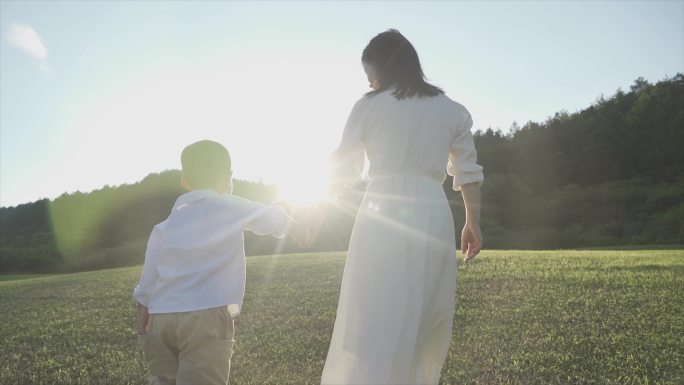 大手牵小手温馨亲子妈妈陪伴孩子逆光背影