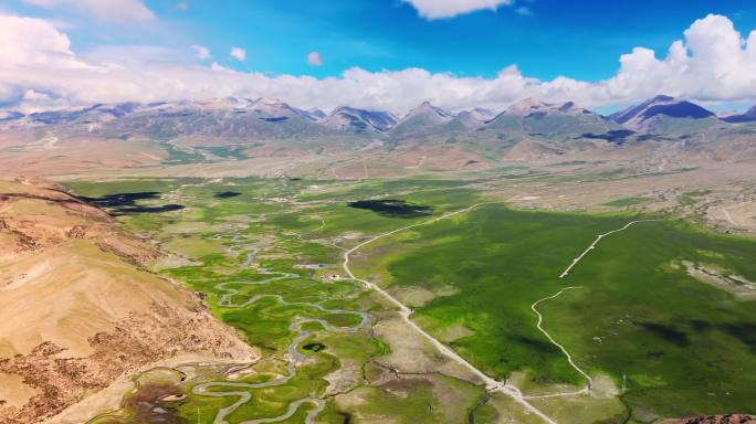 西藏那曲雪山脚下山谷中草原上的河流航拍