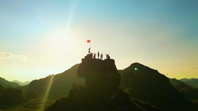 青年团队登顶山峰在山顶举起五星红旗爱国家