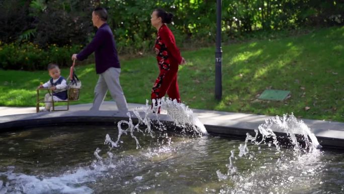 带孙孙的爷爷奶奶外公外婆走过水景喷泉