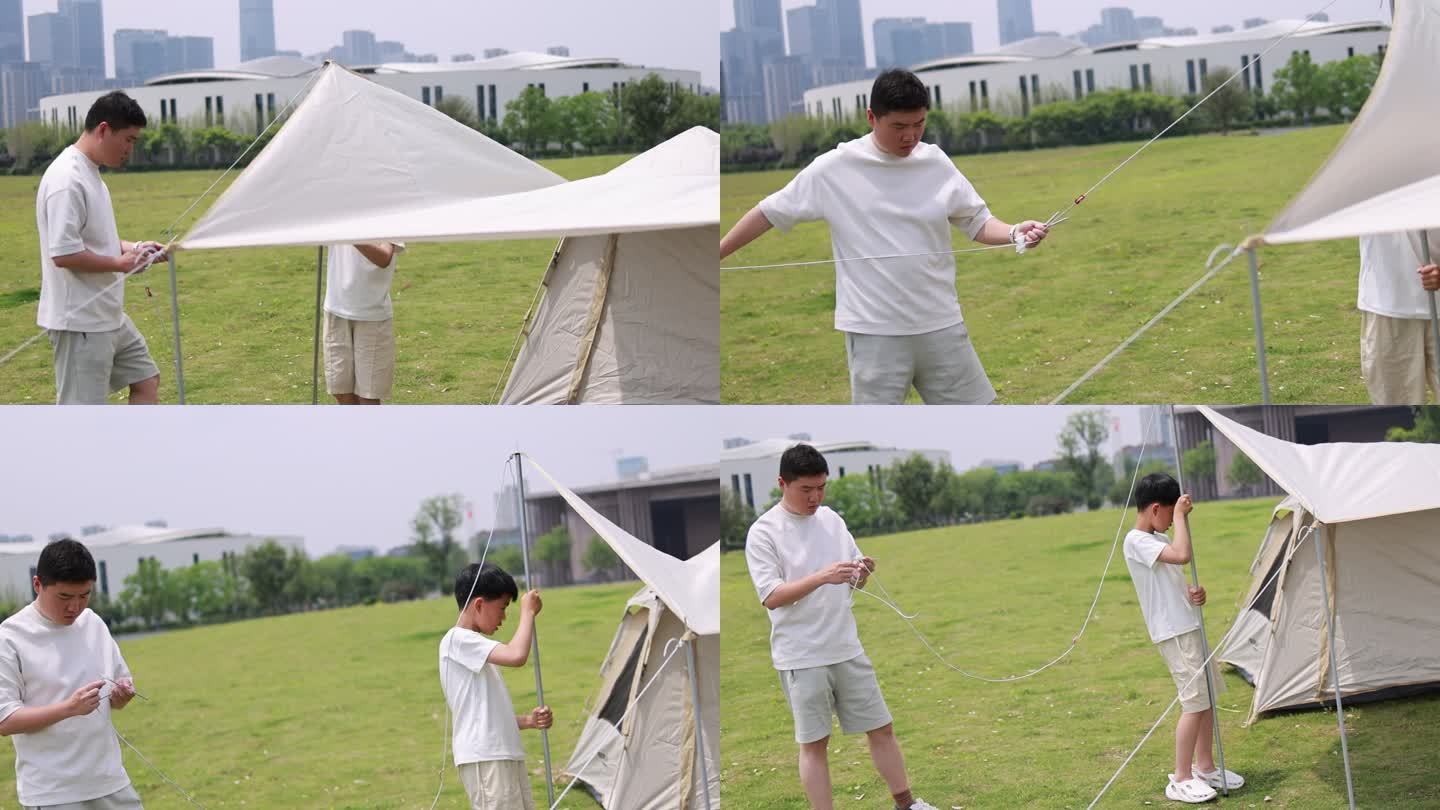 年轻家庭户外露营，父子合作搭帐篷慢镜
