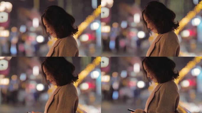 秋天夜晚美女在成都街头看手机微笑快乐