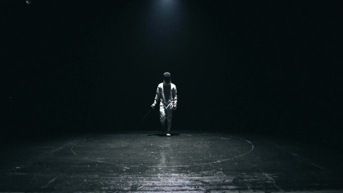 充满自信的男子击剑运动员从黑暗中走来
