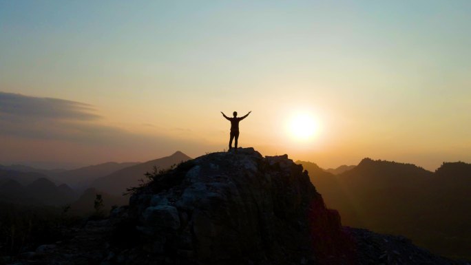 一个人站在山顶张开双臂拥抱太阳向往自由