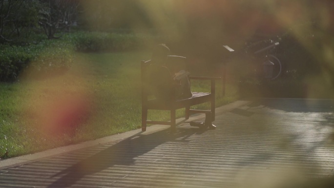 阳光下女孩坐下小区的长椅上读书