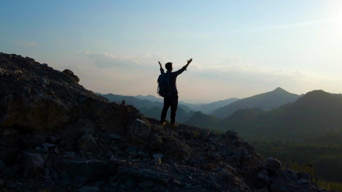 男人站在山顶举手呐喊张开双臂拥抱未来蓝天