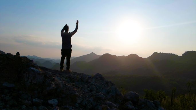 男人站在山顶挥手呐喊释放压力向往自由攀登