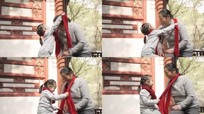 可爱的小女孩在公园里给奶奶戴红围巾