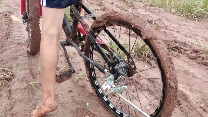 泥洼路段泥坑雨天泥泞路小孩子光脚推山地车