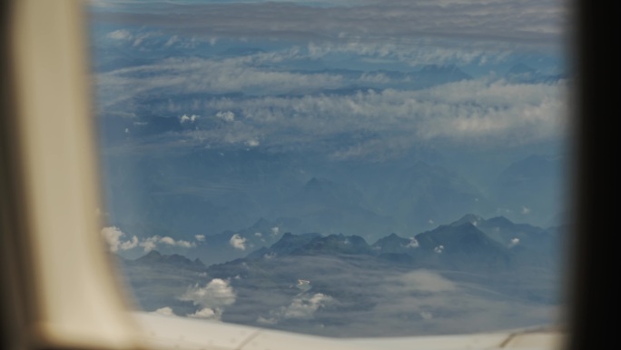 从飞机窗户看窗外崇山峻岭水墨画云层山峰